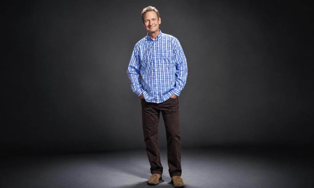 Ryan Stiles standing in a studio wearing a blue checkered shirt